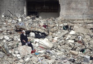 Una donna siriana seduta sulle rovine della sua casa. AP Photo/Abdullah al-Yassin