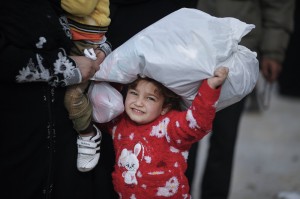 Libano. Leila, 5 anni, con il pacco di vestiti nuovi per l'inverno acquistati da sua madre con i voucher di Oxfam. Credits: Sam Tarling