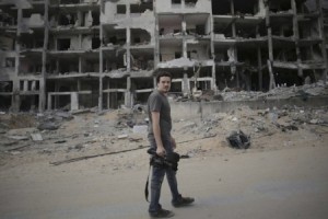 Associated Press video journalist Simone Camilli walks against a backdrop of destroyed buildings in Beit Lahiya in the Gaza Strip