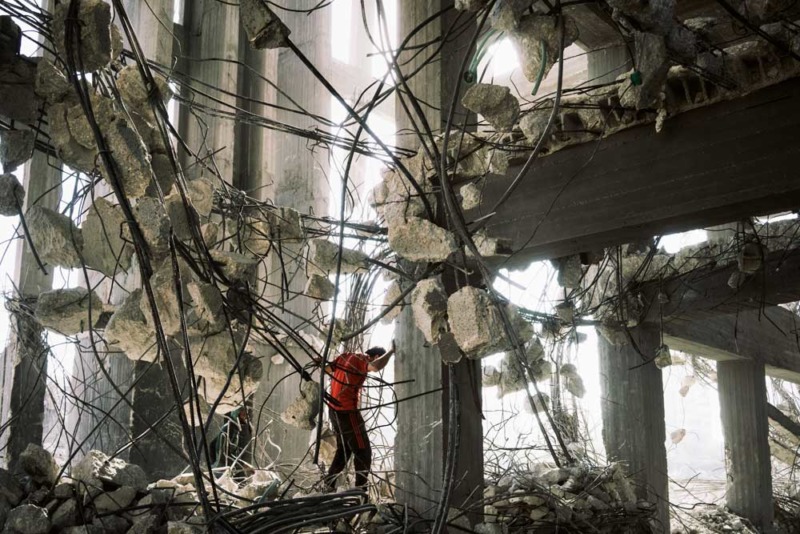 Un lavoratore ricicla barre d'acciaio rinforzate da un edificio che è stato bombardato