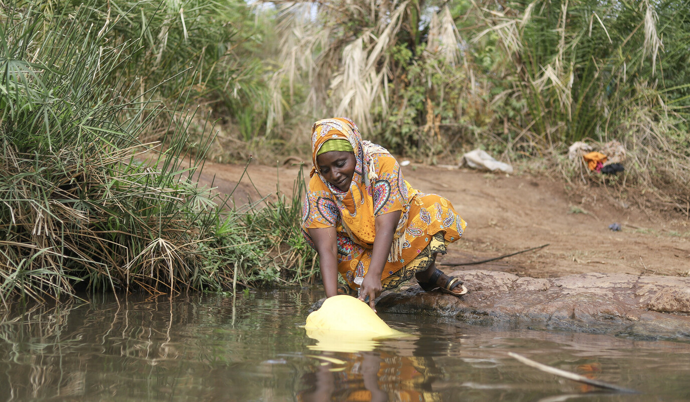 Crisi idrica: una donna raccoglie acqua dal fiume per la sua famiglia