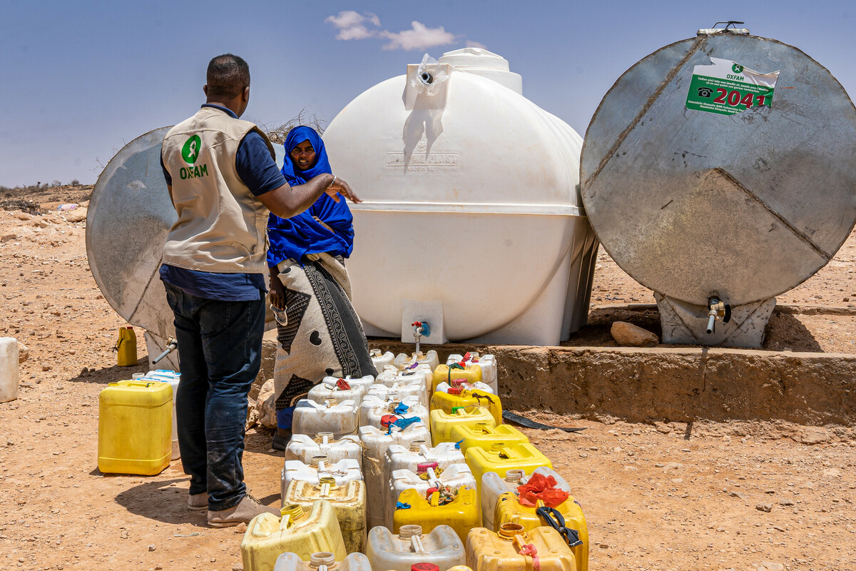 Un volontario Oxfam porta taniche di acqua alla popolazione locale