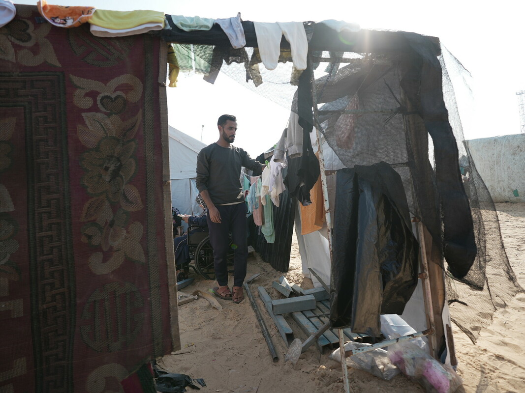 Ammar mentre stende gli abiti del nipote accanto alla loro tenda. Foto: Alef Multimedia/ Oxfam 