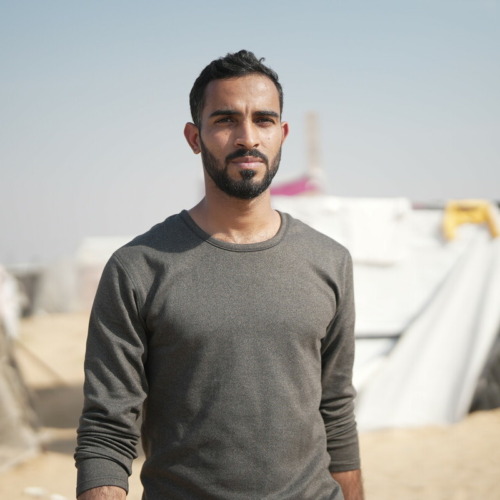 Ammar* in piedi davanti alla sua tenda ad Almawasi, nel sud di Gaza.