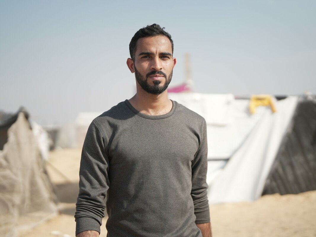 Ammar* in piedi davanti alla sua tenda ad Almawasi, nel sud di Gaza.