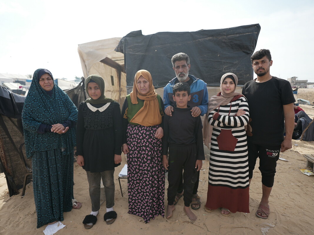 Muna con il marito, le figlie e altri membri della famiglia di fronte alle tende che danno loro riparo ad Al Mawasi. Foto: Alef Multimedia/ Oxfam