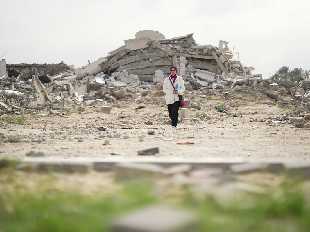 Fidaa Shurrab, direttrice dei progetti presso Atfaluna for Deaf Society a Rafah, si trova di fronte a un edificio distrutto nella Striscia di Gaza mentre va al lavoro.