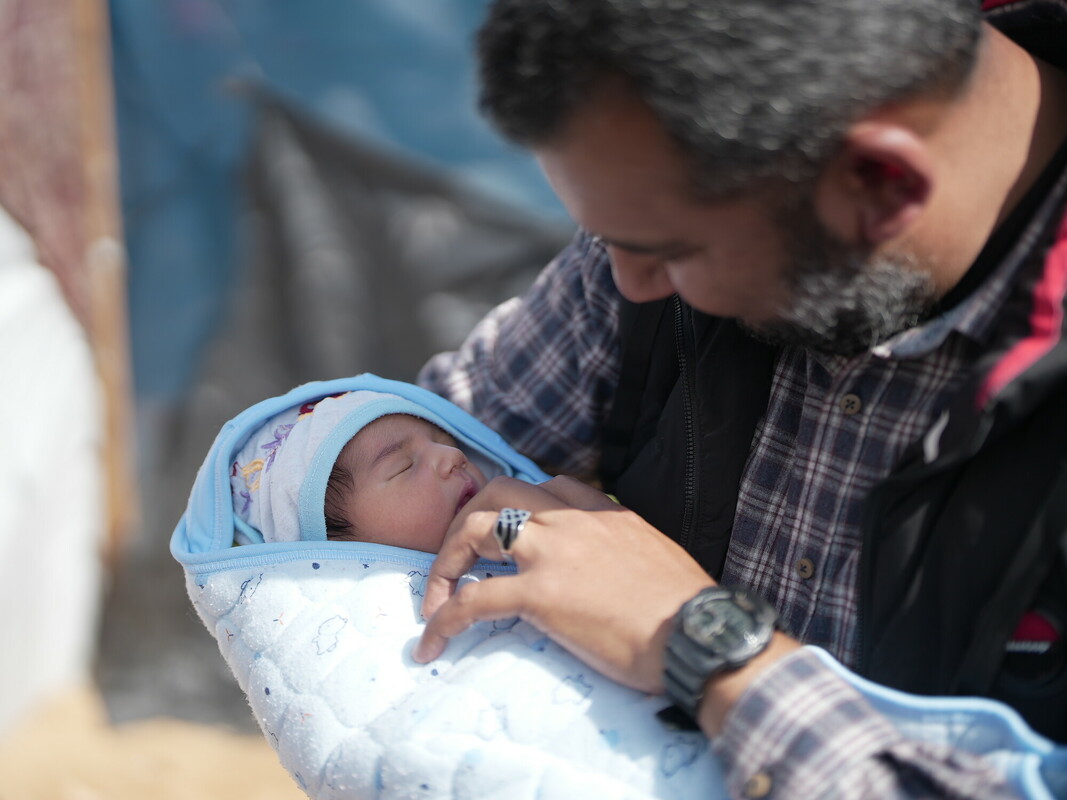 Asif posa davanti alla tenda con il suo quarto figlio, venuto al mondo nel campo di Rafah.