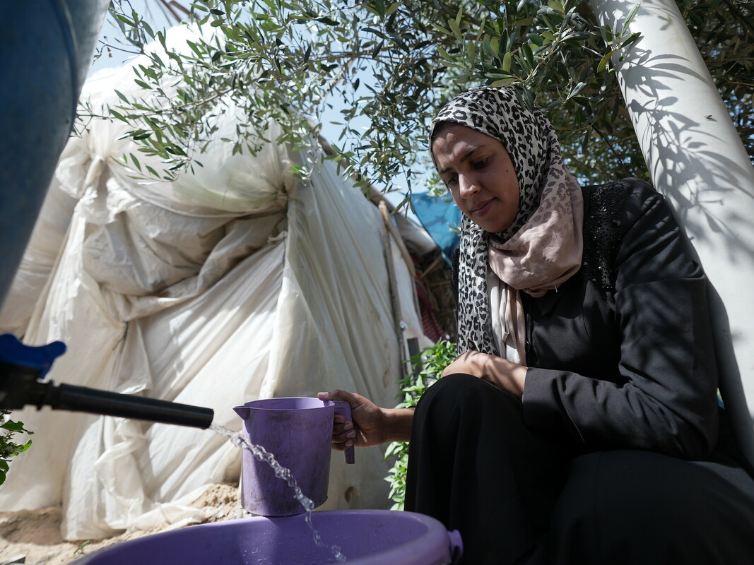 Wafa attinge dell’acqua a una cisterna installata da Oxfam nel campo di Al-Mawasi, in cui si sono rifugiate migliaia di persone. Foto: Alef Multimedia/Oxfam