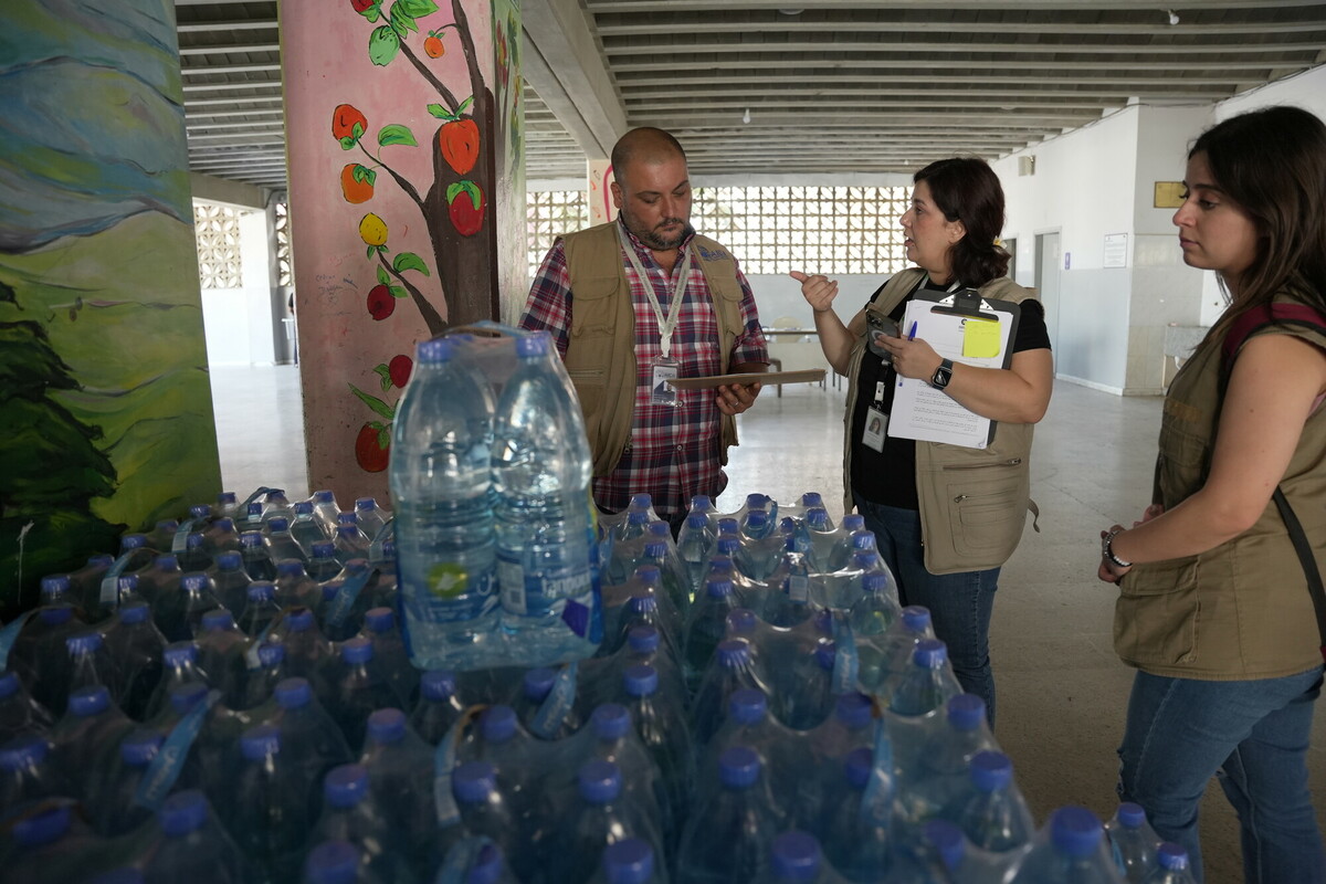 Lo staff di Oxfam insieme ai colleghi dell’associazione partner AICA (Alawite Islamic Charity Association) distribuisce acqua alle persone sfollate in un rifugio collettivo nel Nord del Libano. Foto: Jean Hatem / Oxfam