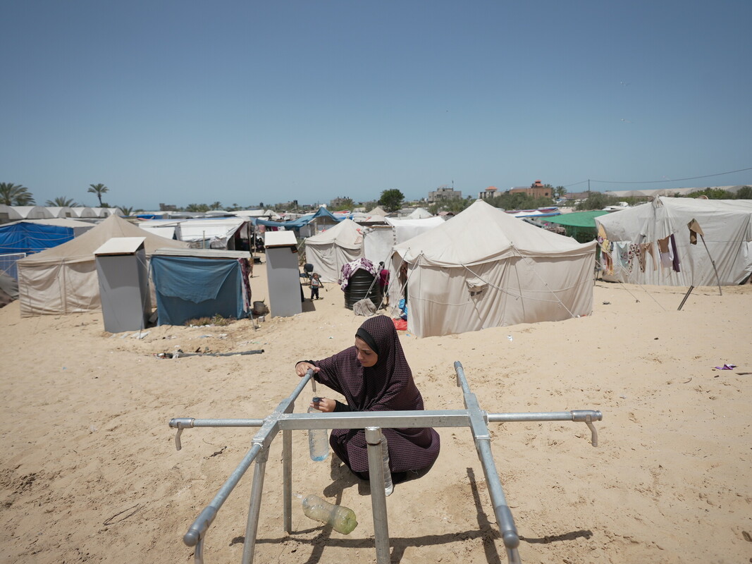 Una donna palestinese riempie bottiglie d'acqua dal serbatoio idrico di Oxfam, installato nella zona di Al-Mawasi, nella provincia di Khan Yunis.