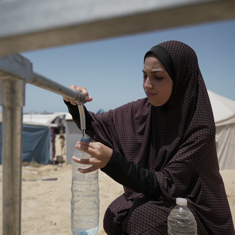Duaa Abu Sabha sta riempiendo le bottiglie d'acqua dal serbatoio idrico di Oxfam, installato nella zona di Al-Mawasi, nel governatorato di Khan Yunis.