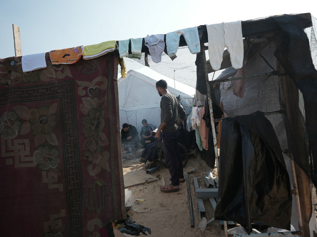 Uomo palestinese sfollato fa il bucato, appendendo con cura i vestiti appena lavati ai lati della tenda della sua famiglia ad Almawasi, Khan Younis. Credit: Alef Multimedia Company/ Oxfam 