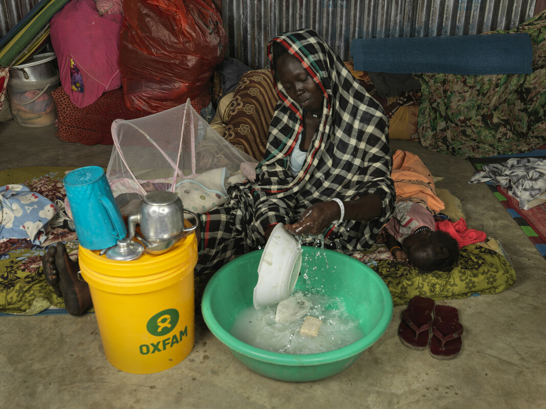 Achol Ring Tong Longar, 21 anni, lava i piatti nella sua tenda in Sud Sudan, dopo essere fuggita dal Sudan devastato dalla guerra. Credit: Peter Caton/Oxfam