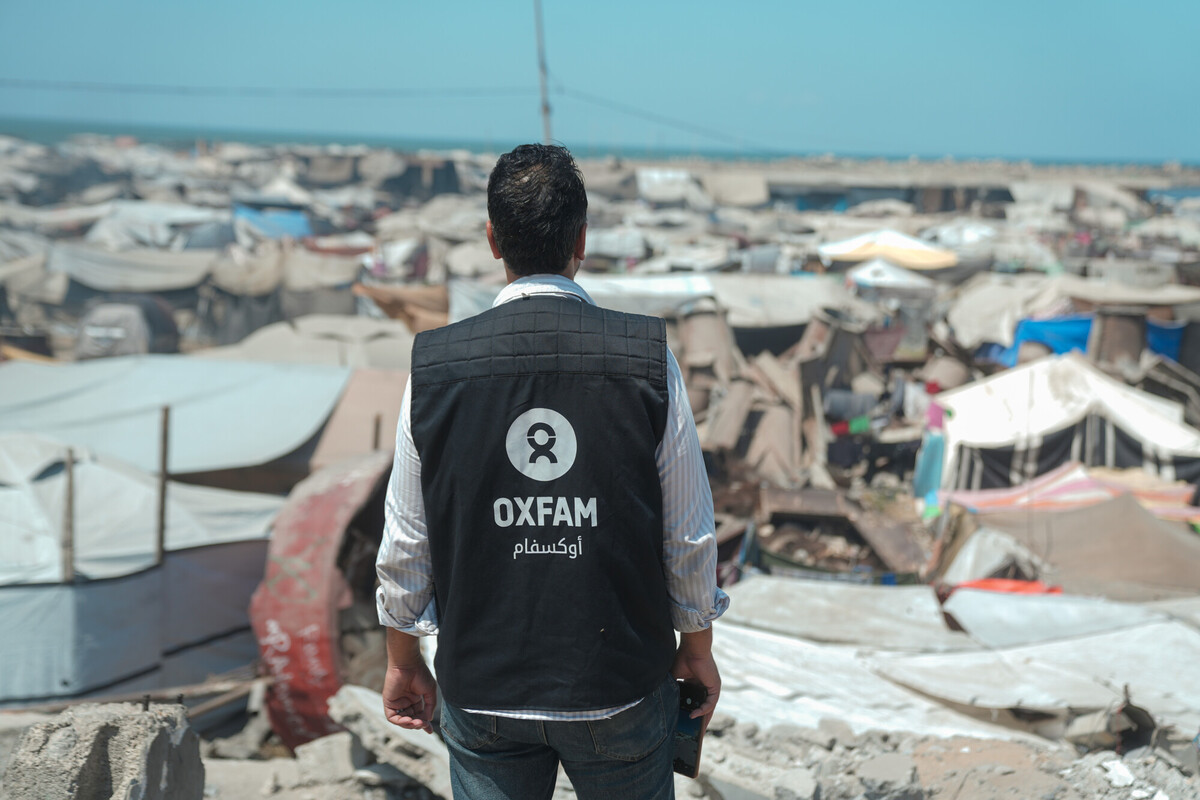 Un operatore di Oxfam cammina tra le tende e le macerie nella città di Gaza