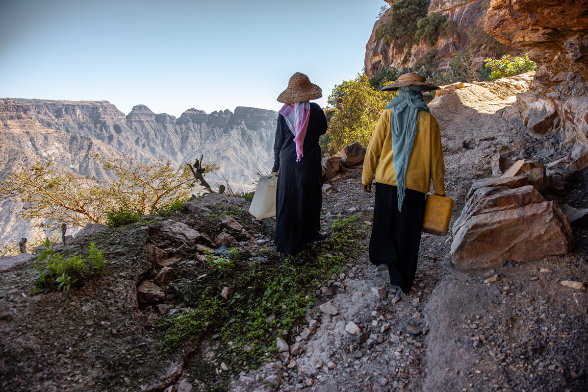 Prima dell'intervento di Oxfam, Abeer trasporta un contenitore d'acqua vuoto, percorrendo lunghe distanze e scalando ripide colline sotto il sole. Nonostante la stanchezza, sopporta il viaggio, determinata a garantire acqua pulita per le necessità quotidiane della sua famiglia. Credit: Ahmed Al-Basha / Oxfam Intermón
