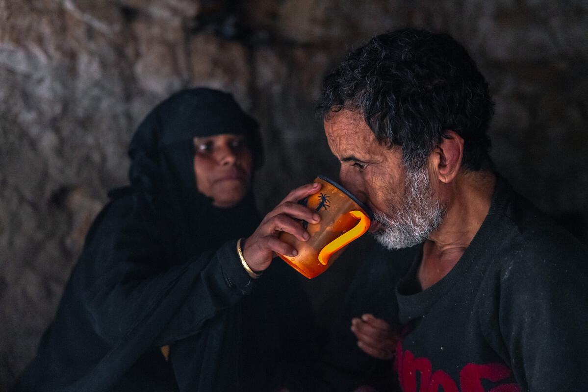 Warda Abdo aiuta il marito disabile a sedersi e bere un bicchiere d'acqua all'interno della casa in cui vivono, nel quartiere di Al Shamayatain. Credit: Ahmed Al-Basha / Oxfam Intermón