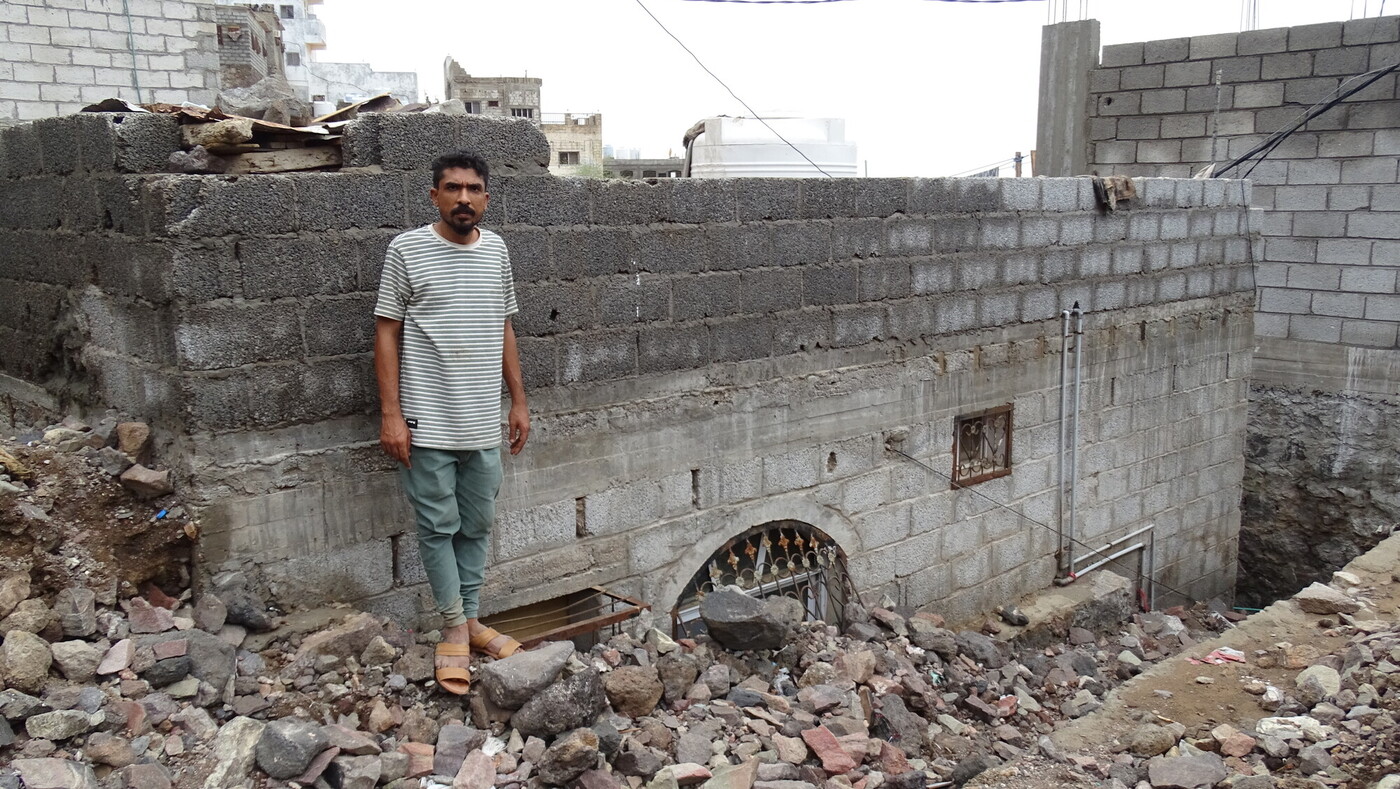 Un uomo in piedi accanto alla sua casa sepolta dalle macerie nel sud dello Yemen, colpito da devastanti alluvioni. Credit: Abdulbari Othaman/Oxfam