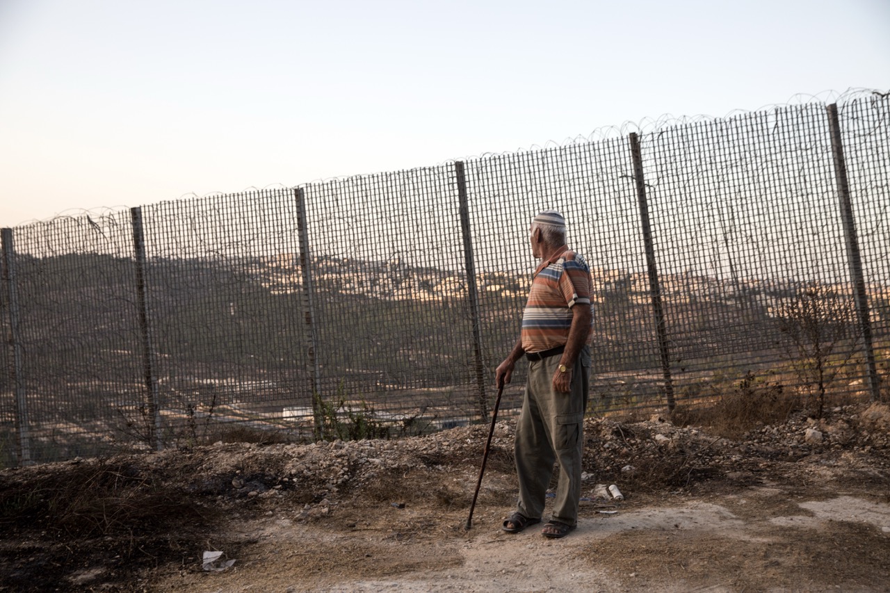 Un uomo palestinese, originario di Betlemme, del villaggio di Al Walajeh, dove i palestinesi ricevono numerosi ordini di demolizione. L'uomo è in piedi accanto al muro di separazione che si affaccia su Gerusalemme