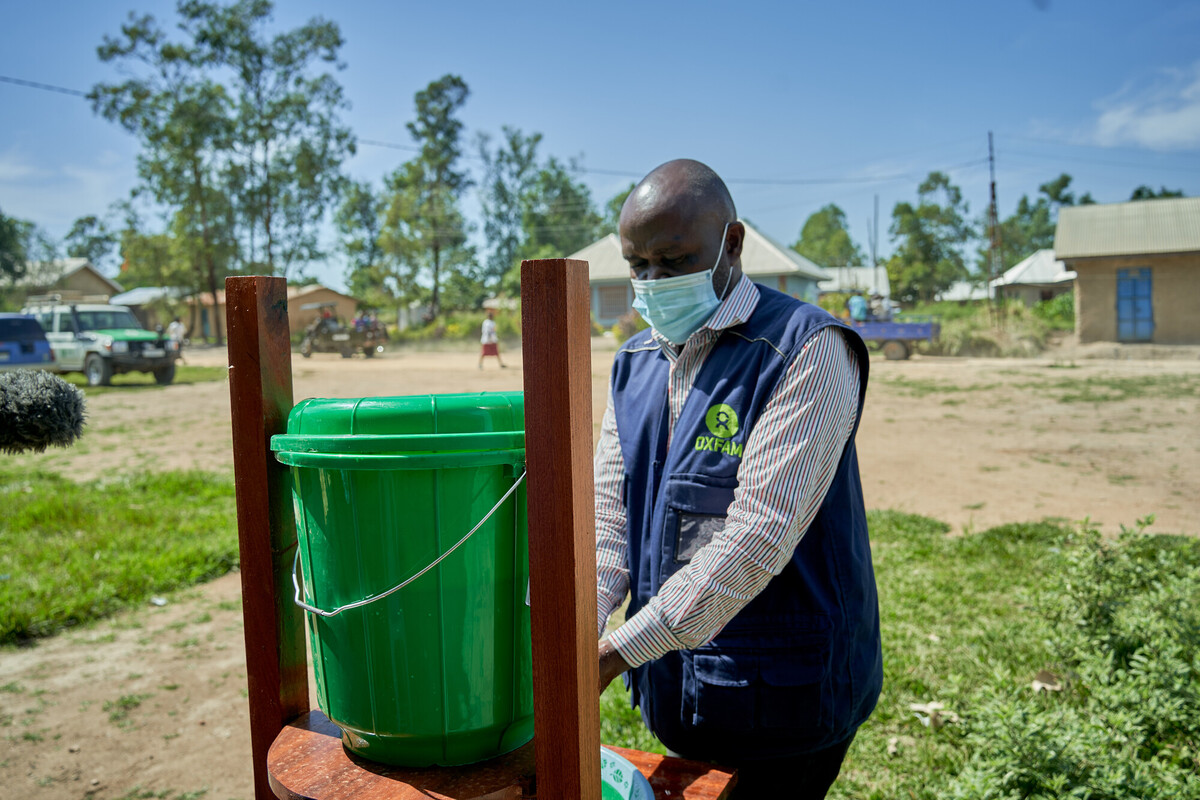 Il responsabile dei progetti WASH di Oxfam mentre utilizza una postazione per il lavaggio delle mani. Il lavaggio delle mani è un elemento fondamentale nella prevenzione dell'Ebola. Credit: Azaria Muhongya / Oxfam