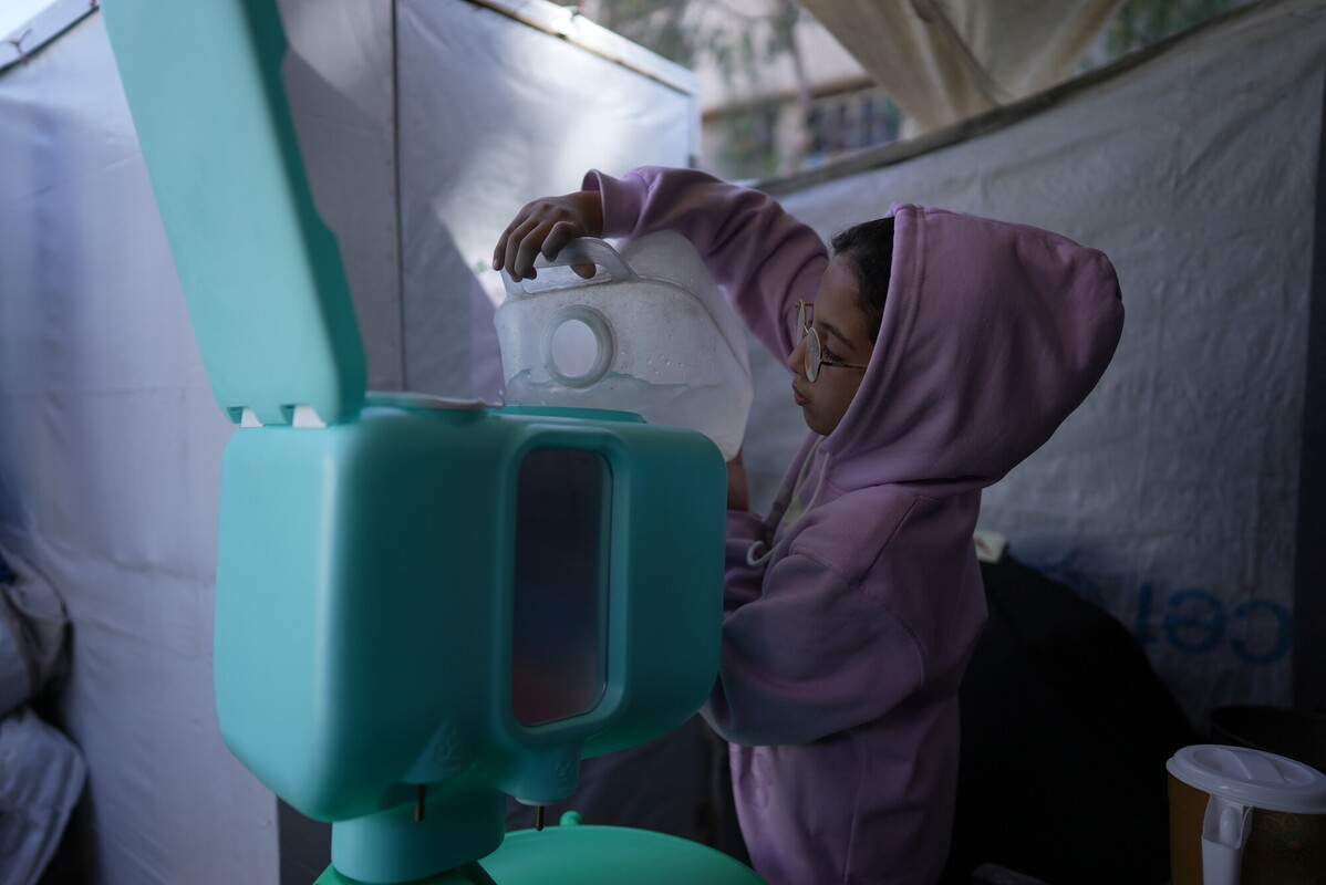 La figlia di Rania riempie la postazione per il lavaggio delle mani fornita da Oxfam
