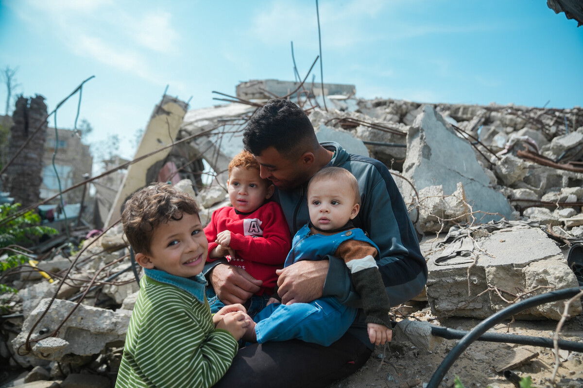 Mohammed seduto sulle macerie della sua casa a Gaza insieme ai suoi tre figli