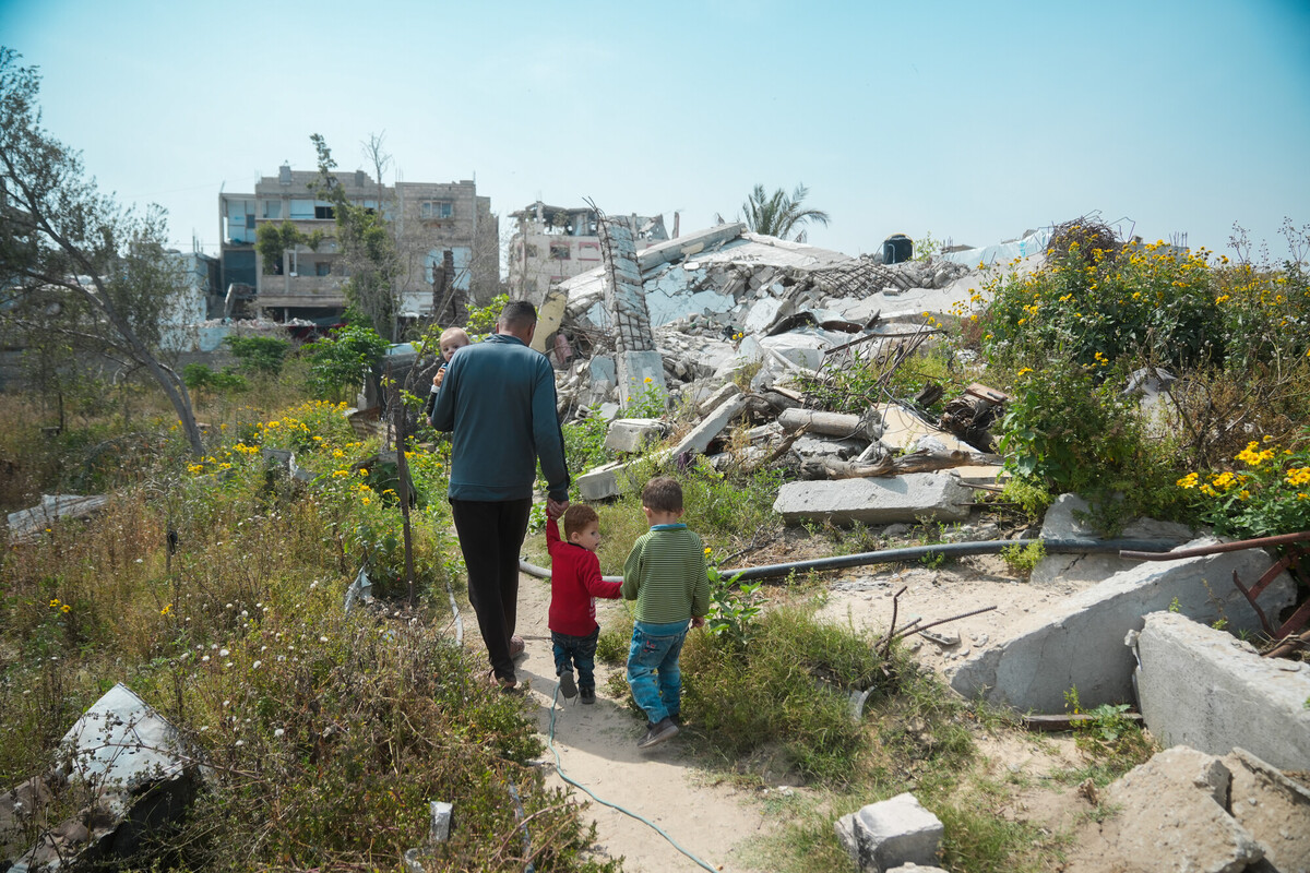 Mohammed passa davanti alla sua casa distrutta a Gaza, insieme ai suoi tre figli. Credit: Alef Multimedia/ Oxfam